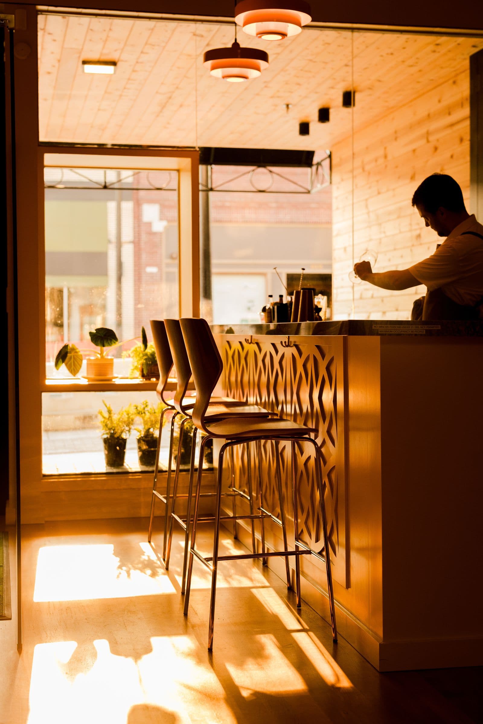 Late afternoon sun across the Kismet bar as a bartender polishes glasses