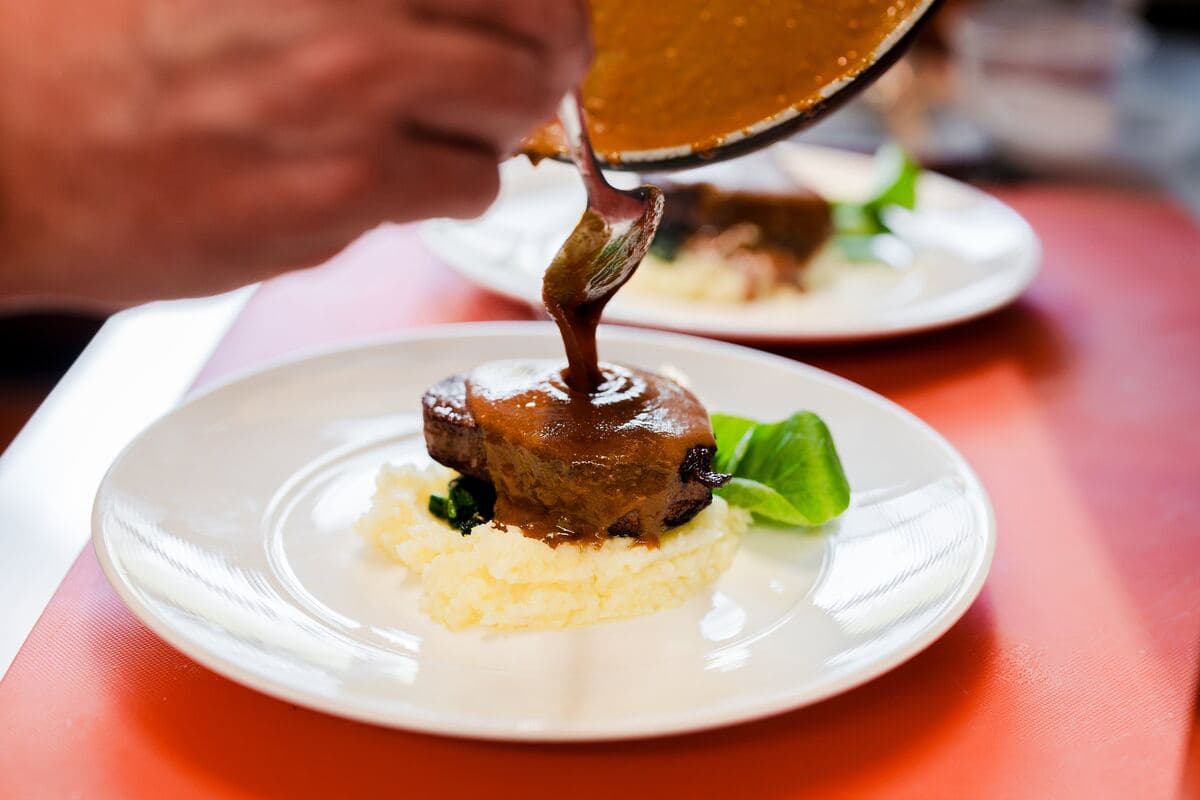 Demi-glace poured over beef tenderloin on potato purée